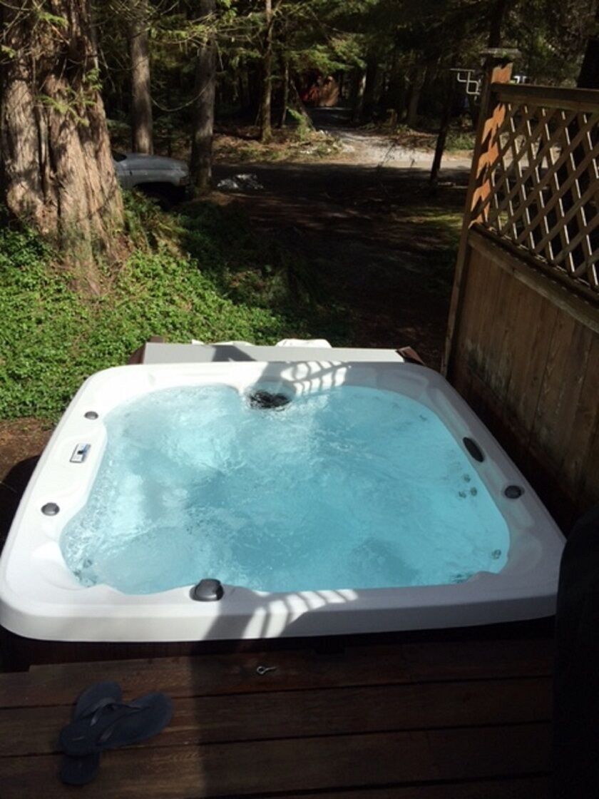 A hot tub on a wooden deck surrounded by trees.