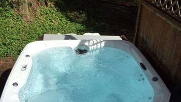 A hot tub on a wooden deck surrounded by trees.