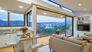 Cozinha moderna com uma janela grande, área de jantar com sofá e vista para o horizonte da cidade.