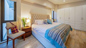 Um quarto com uma cama, mesas de cabeceira, uma cadeira e um guarda-roupa.