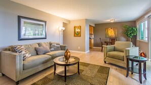 A living room with a sofa, armchair, coffee table, and a dining area with a table and chairs.
