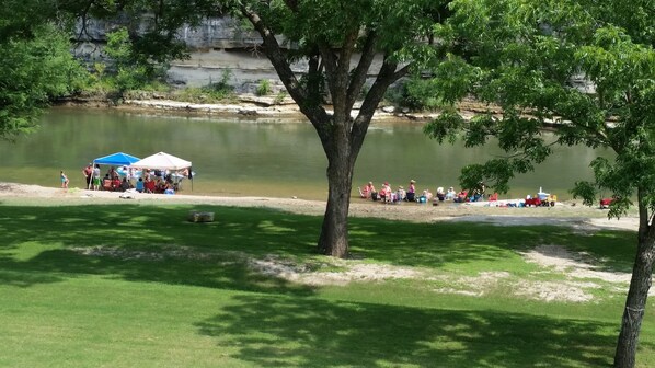 Un parque junto al lago con un área cubierta por carpas y mesas de picnic.