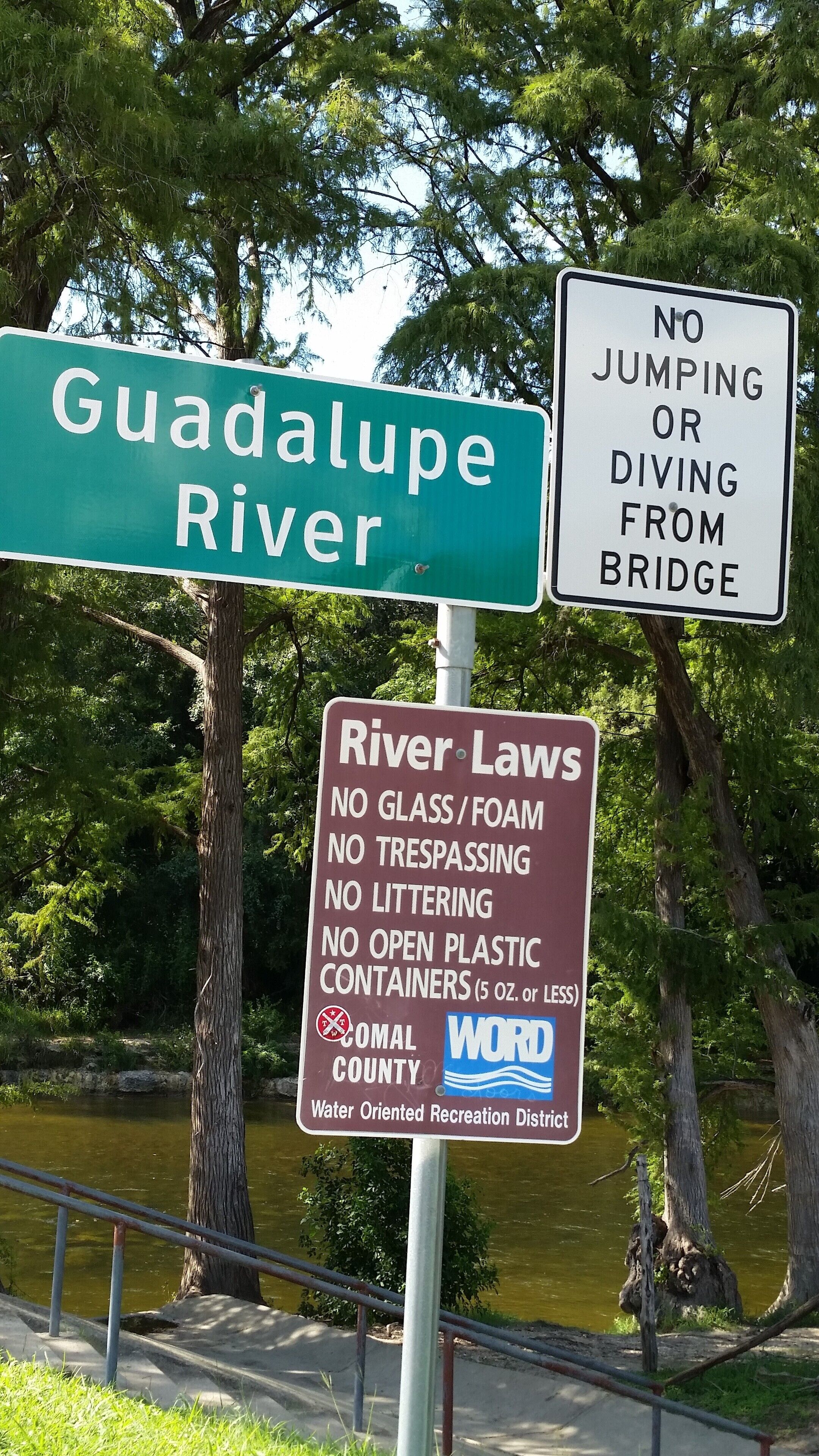 Un cartel con varias indicaciones, incluyendo una para el Río Guadalupe y otra que detalla las leyes del río.