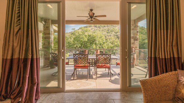 Une pièce dotée d’une porte-fenêtre coulissante donnant sur une terrasse extérieure avec une table et des chaises.