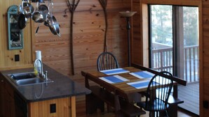 L'intérieur d'une cabane en bois comprend une cuisine, un coin repas et de grandes fenêtres.
