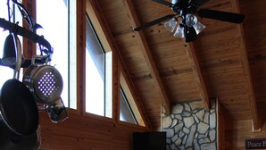 L’intérieur d’un chalet en bois comprend une cuisine, un coin repas et une cheminée en pierre.