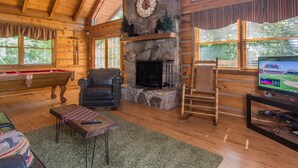 A cozy living room with a stone fireplace, a pool table, and a television. - Cloud Nine: Charming Mountain Cabin, Amazing Views!  Now featuring a new bed! (Sevierville)