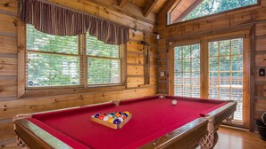 A pool table in a wooden room with large windows and a view of trees. - Cloud Nine: Charming Mountain Cabin, Amazing Views!  Now featuring a new bed! (Sevierville)