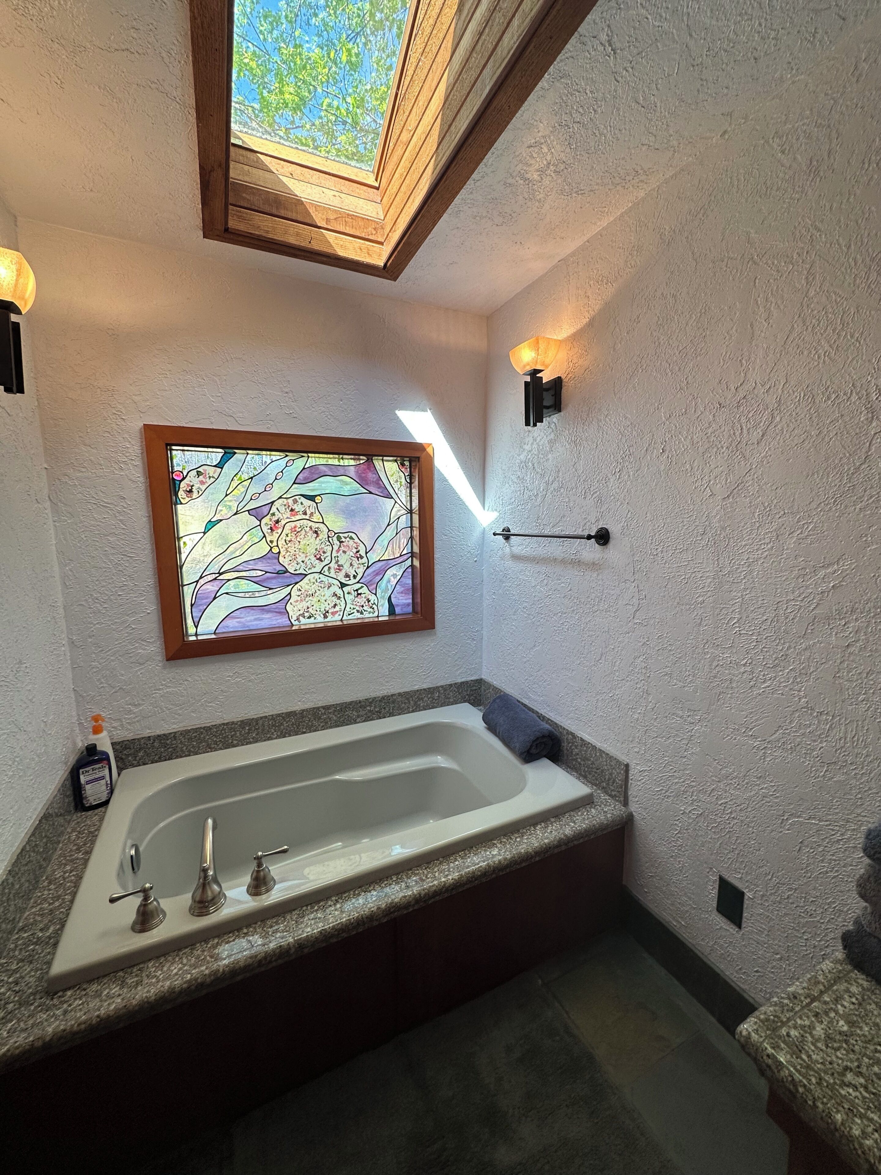 A bathroom with a freestanding bathtub, a stained glass window, and a towel rack.
