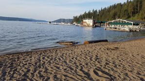 Une plage avec une jetée en bois et un bâtiment doté d’un toit végétalisé.
