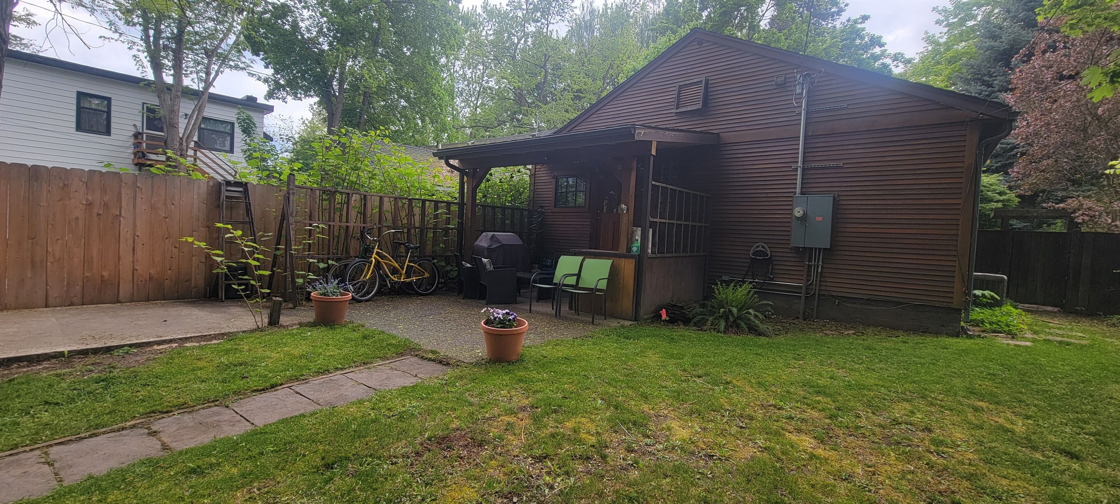 A wooden cabin with a porch, a bicycle, and a grill area.