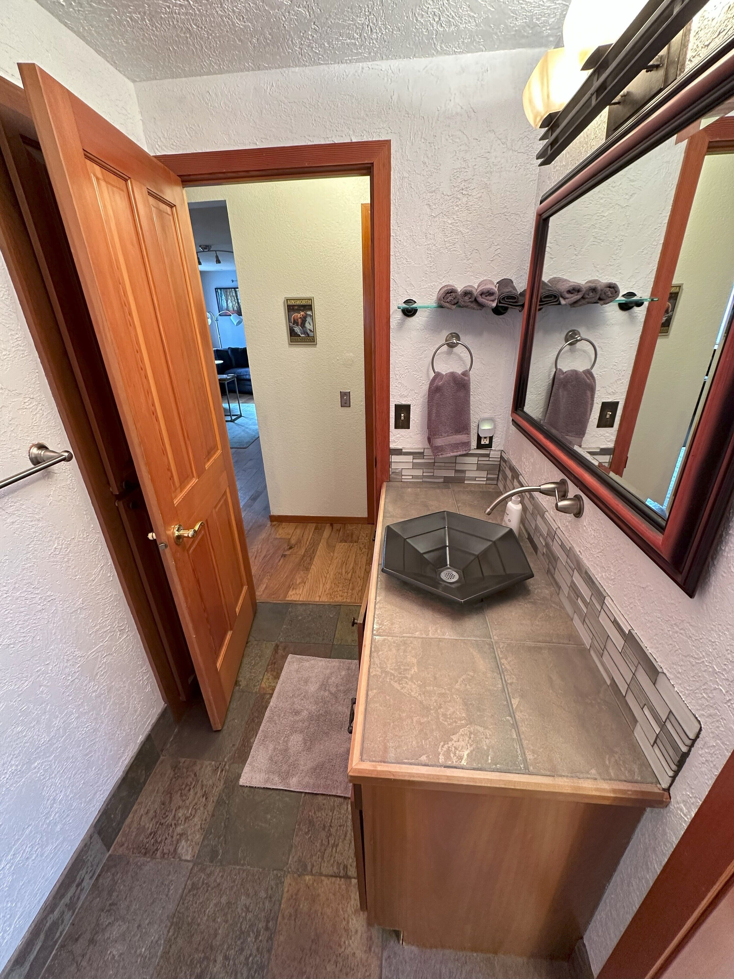 A bathroom with a wooden vanity, a large mirror, and a towel rack.