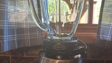 A kitchen with a stainless steel Oster blender on a granite countertop.