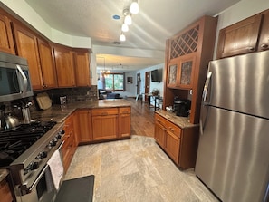 A kitchen with wooden cabinets, a stainless steel refrigerator, and a gas stove. - Modern and unique cottage in perfect downtown CDA location for a great getaway! (Coeur d'Alene)