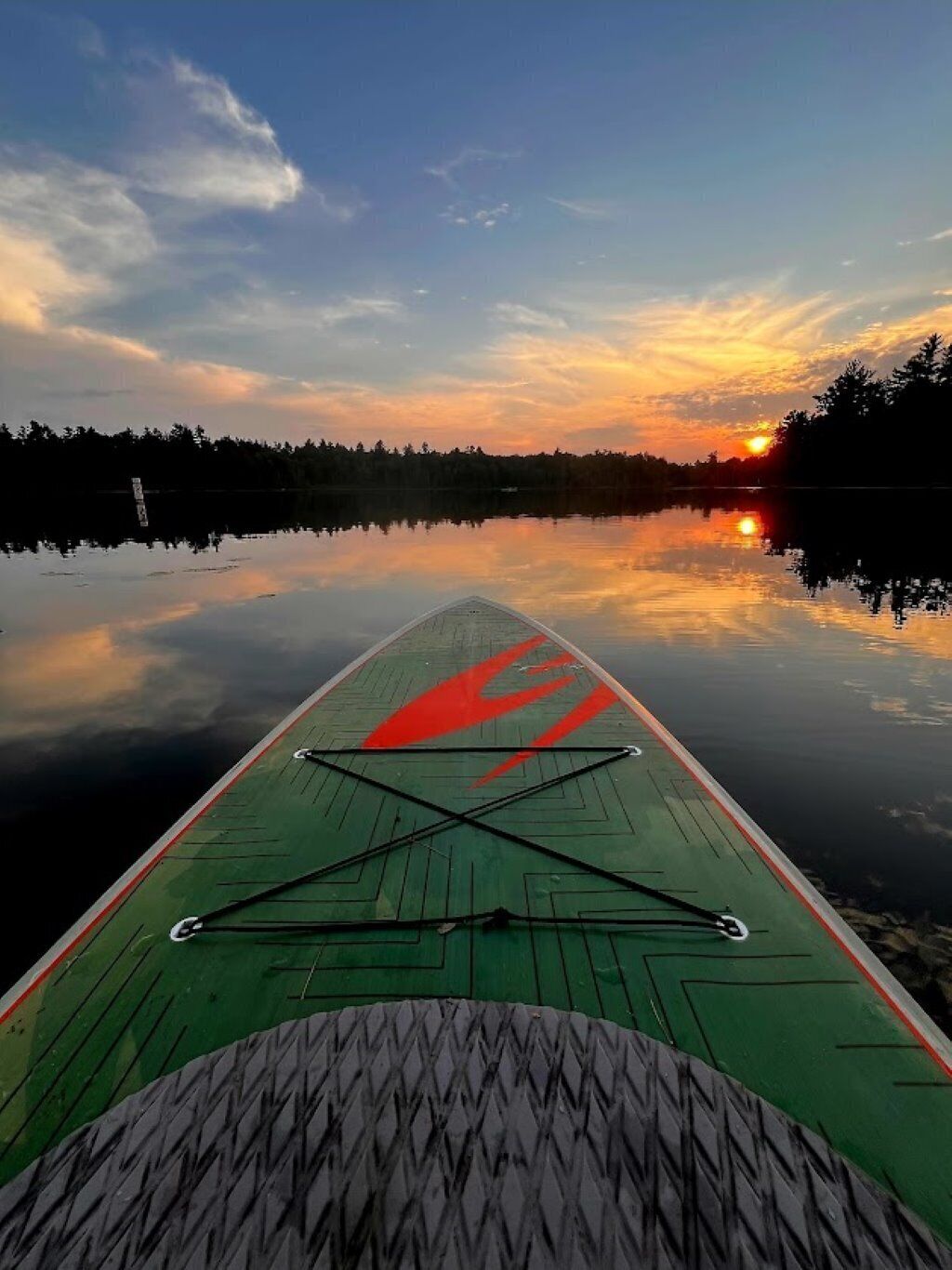 A paddleboard on calm water with a sunset in the background.