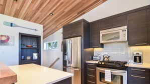 Una cocina moderna con armarios oscuros, electrodomésticos de acero inoxidable y techo de madera.