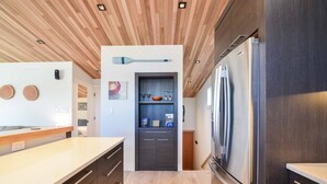 Una cocina moderna con techo de madera, refrigerador empotrado y un mueble de madera oscura.