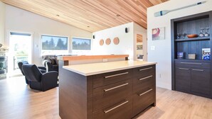Una cocina moderna con armarios de madera, una isla central y un comedor con sillas.