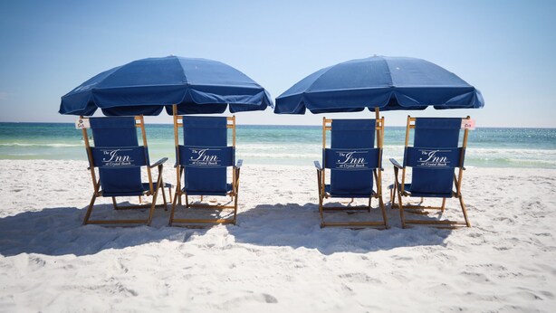 Four beach chairs with blue umbrellas at The Inn at Crystal Beach.
