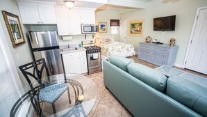 A compact living space with a kitchenette, a dining area, and a bedroom.