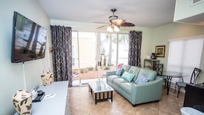 A living room with a sofa, coffee table, TV, and a ceiling fan.