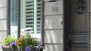 A building with a dark brown door, a window with blinds, and a number '1401' on the wall.