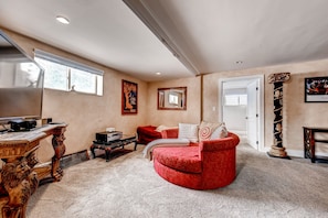 A living room with a red sofa, a wooden coffee table, a fireplace, and a large window. - Luxury that is close to downtown and easy access to Red Rocks! (Lakewood)