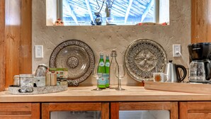A kitchen counter with decorative plates, bottles, and a coffee maker.