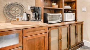 A kitchen with wooden cabinetry, a coffee maker, a toaster, and a microwave on the counter.