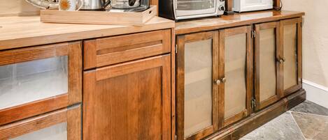 A kitchen with wooden cabinetry, a coffee maker, a toaster, and a microwave on the counter.