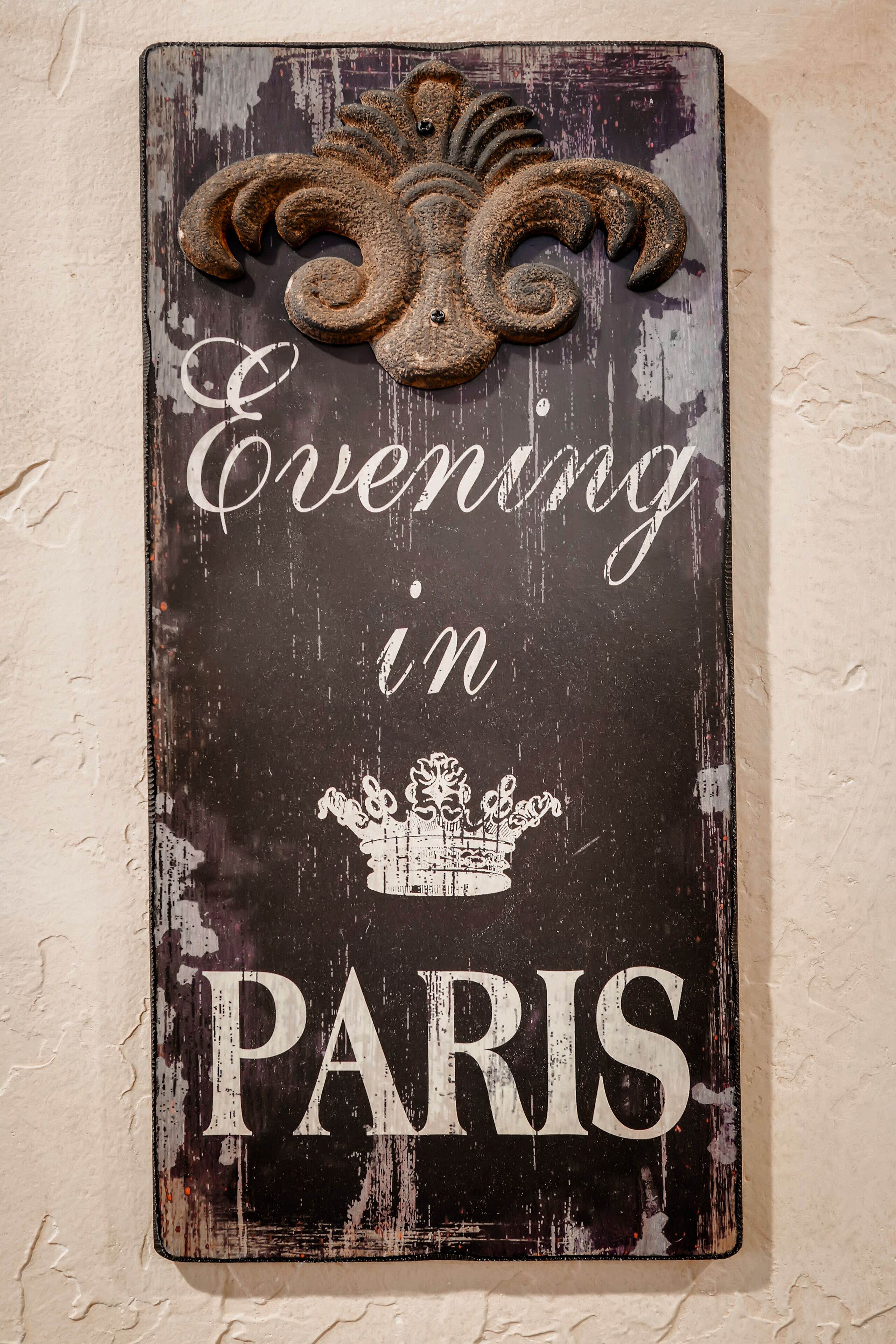 A weathered sign with the text "Evening in Paris" and a crown illustration.