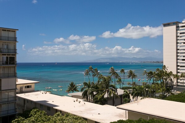 Blick auf die Küste mit blauem Himmel, Palmen und einem Strand mit Booten.