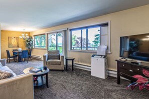 A living room with a sofa, a coffee table, a TV, a heater, and a dining area with chairs and a table. - the Veranda, Best Area, 2 Baths, WD, Jacuzzi bath (Tacoma)