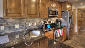 A kitchen with wooden cabinets, stainless steel appliances, a tiled backsplash, and a granite countertop. - Beautifully Renovated Condo, Steps From Main St & Gondola; Very Clean (Breckenridge)