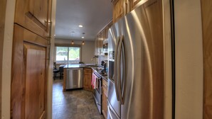 A modern kitchen with stainless steel appliances, wooden cabinets, and a view to the outside. - Beautifully Renovated Condo, Steps From Main St & Gondola; Very Clean (Breckenridge)