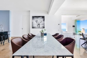 Ein moderner Essbereich mit einem Marmortisch, Ledersesseln und einem großen gerahmten Bild an der Wand.