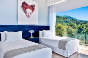 A hotel room with two beds, a large window with a view of a green landscape, and a painting on the wall.