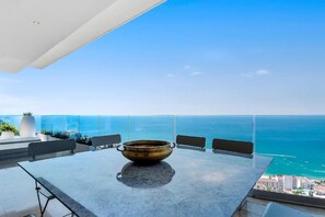 Un balcone con tavolo e sedie, vista sulla costa.