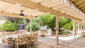 Une terrasse extérieure dotée d’une pergola, d’un barbecue et d’un espace repas avec des chaises et une table.