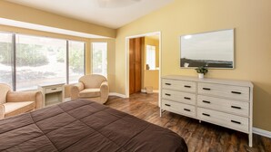 Une chambre à coucher avec un grand lit, un ventilateur de plafond, une commode et une fenêtre avec des stores.