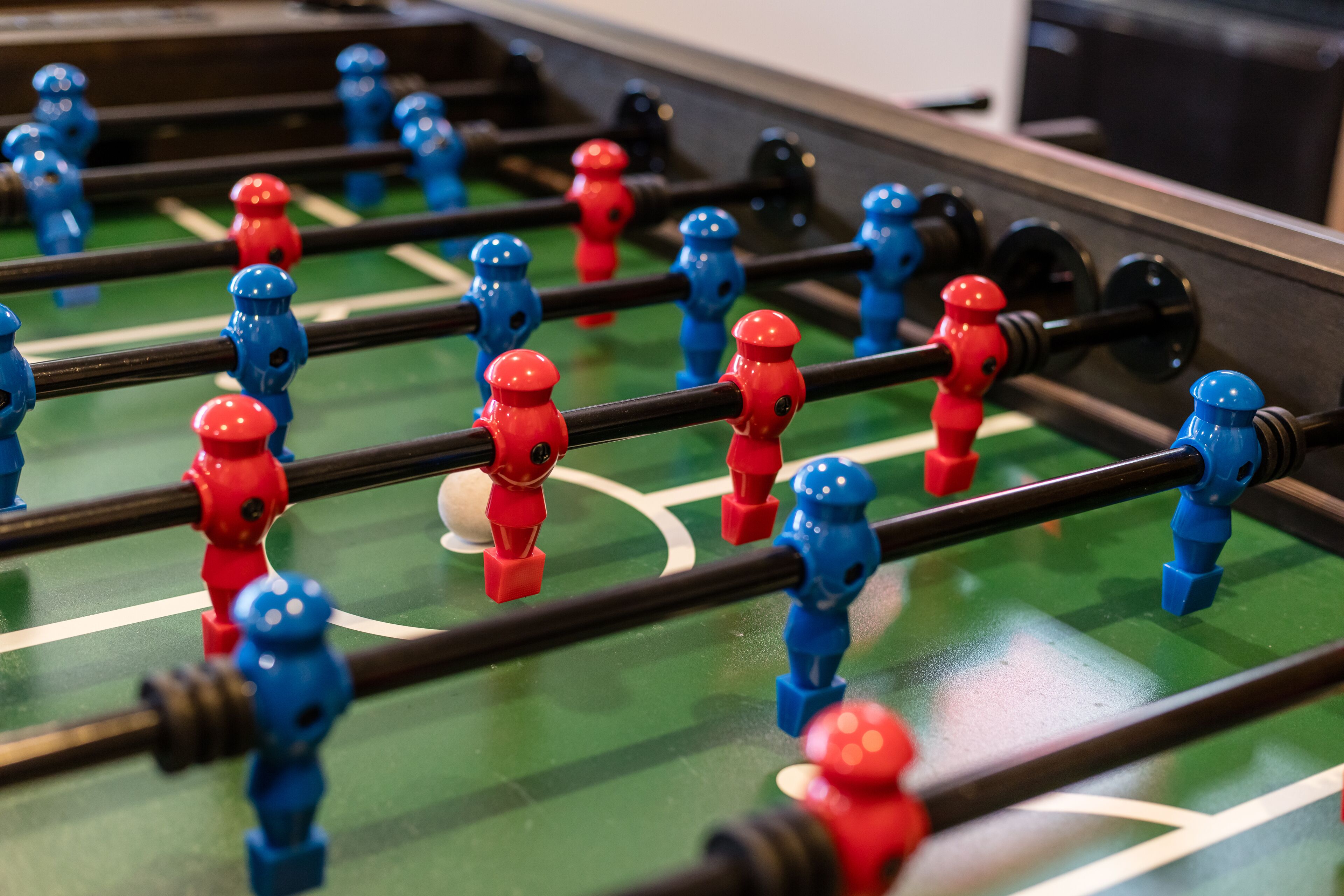 Eine Nahaufnahme eines Kicker-Tisches mit roten und blauen Spielfiguren.
