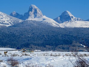 A snow-covered landscape with mountains in the background and a small cabin in the foreground. - Hot Tubs! National Parks Headquarters! Explore Teton Valley, ID & Jackson Hole! (Driggs)