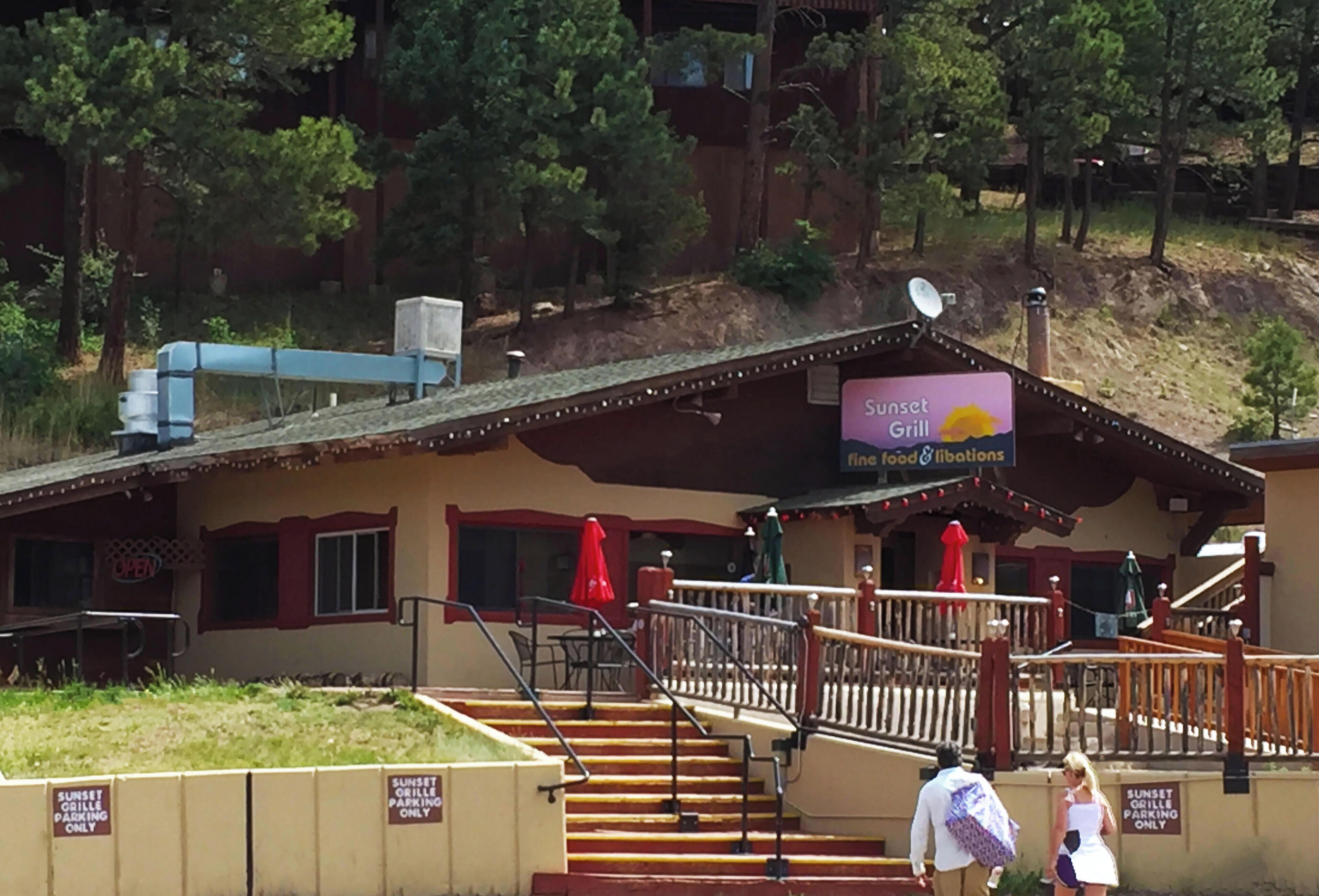 A building with a sign reading "Sunset Grill" and a staircase leading to a deck.