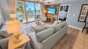 A living room with a sofa, a coffee table, and a TV mounted on a wooden wall. - 4th Flr 1 Bdrm+Bunks/2Bath. Upgraded! Sleeps 6 (Panama City Beach)