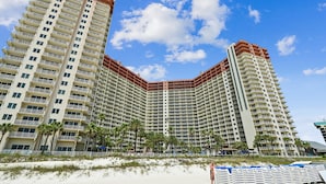 Un hotel moderno de gran altura con varias terrazas, vista al mar y palmeras.