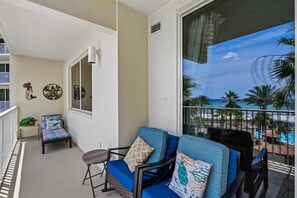 A balcony with a view of the beach, a chair with patterned cushions, and a small table. - 4th Flr 1 Bdrm+Bunks/2Bath. Upgraded! Sleeps 6 (Panama City Beach)