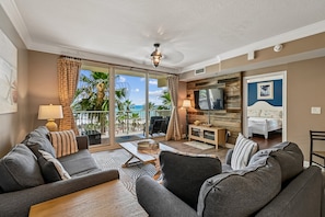 A living room with a sofa, a coffee table, and a view of the ocean.