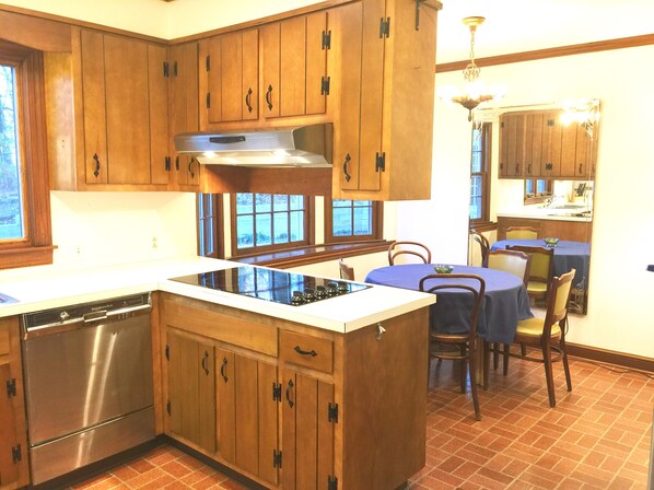 Una cocina con armarios de madera, una estufa empotrada y un comedor con mesa y sillas.
