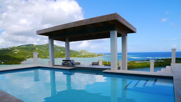 A pool with a wooden deck and a view of the ocean. - Sailor's Rest, a Romantic and Luxurious Sanctuary  (Christiansted)