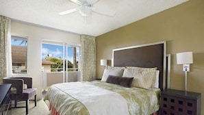 A hotel room with a large bed, a desk, and a chair. There is a window with a view of the outdoors.